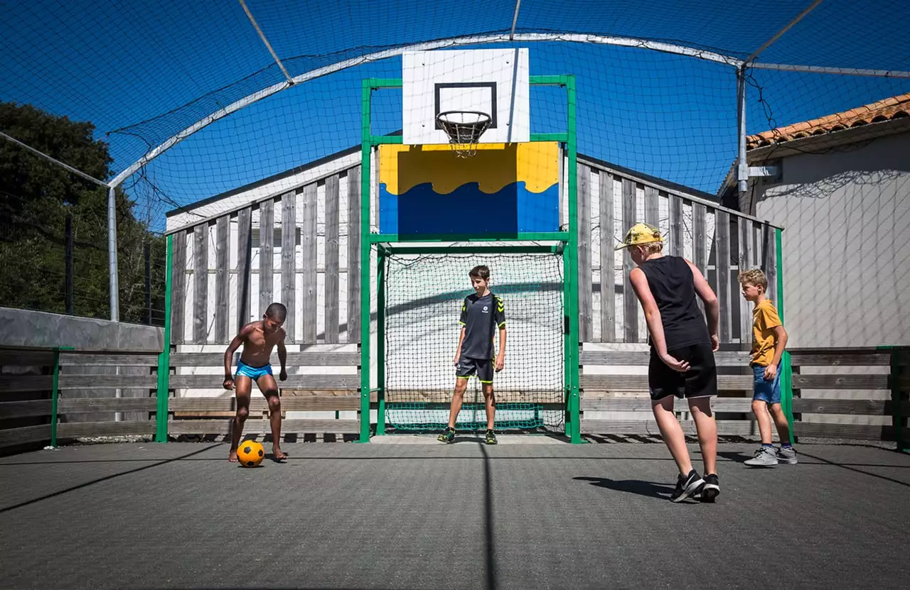 Des enfants qui jouent au foot dans un city stade dans un camping