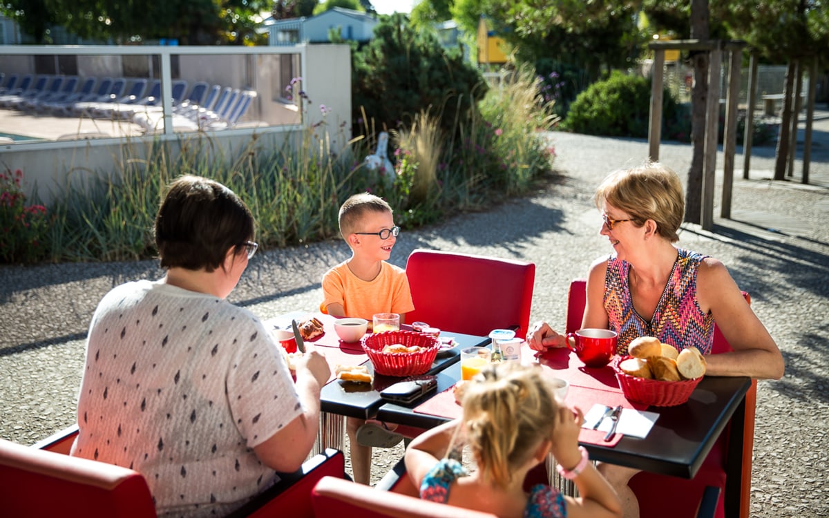 une famille prend son petit déjeuner dans l'espace convivial du camping